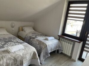 łóżka obok balkonu w pokoju w willi anna w gródku nad dunajcem