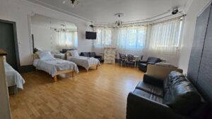 pokój z trzema łózkami komodą i stolikiem z krzesłami w willi anna w gródku nad dunajcem